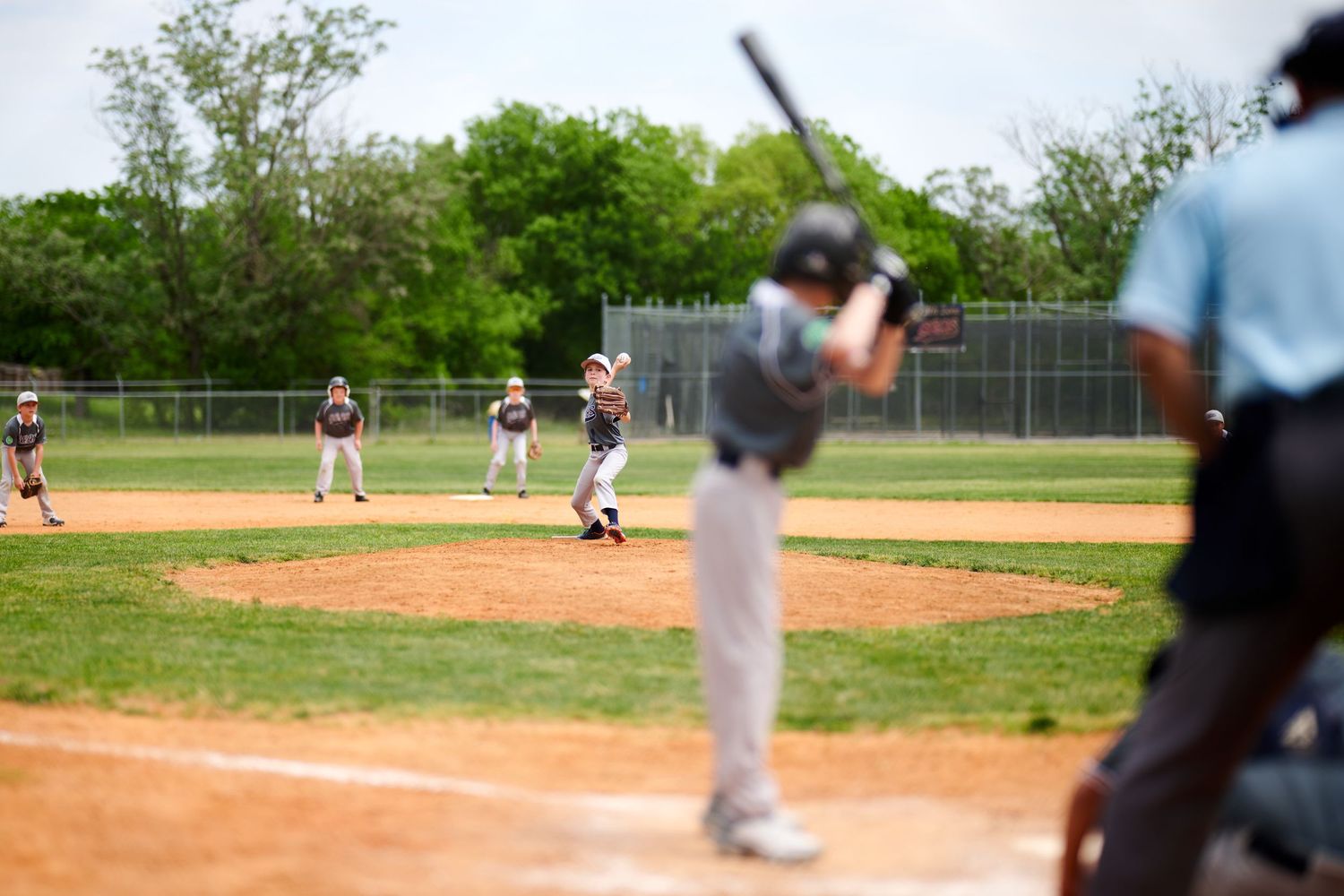 A baseball game in progress on a sunny day with players positioned on the diamond field.