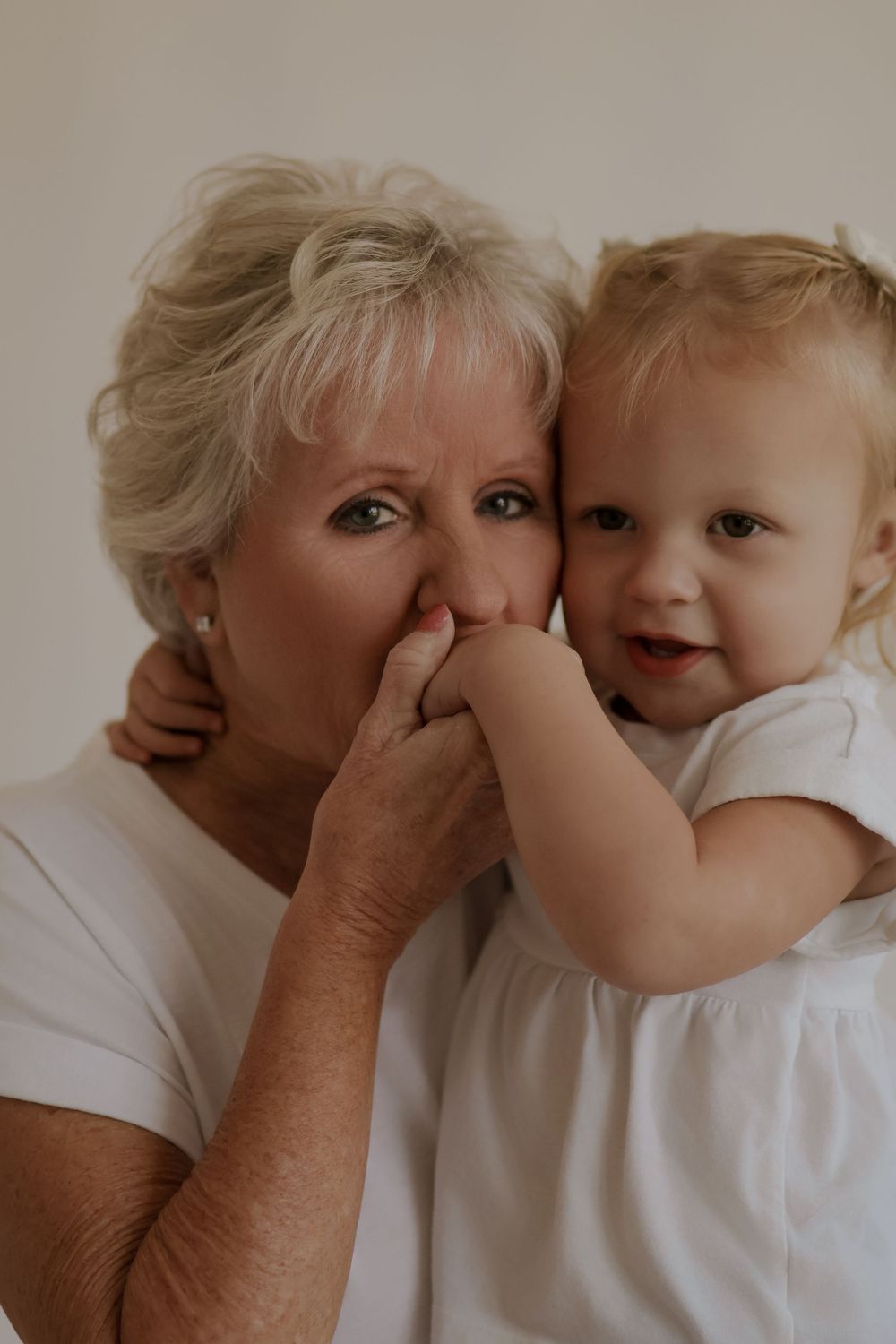 Intimate portrait session capturing tender moments against beige backdrop.