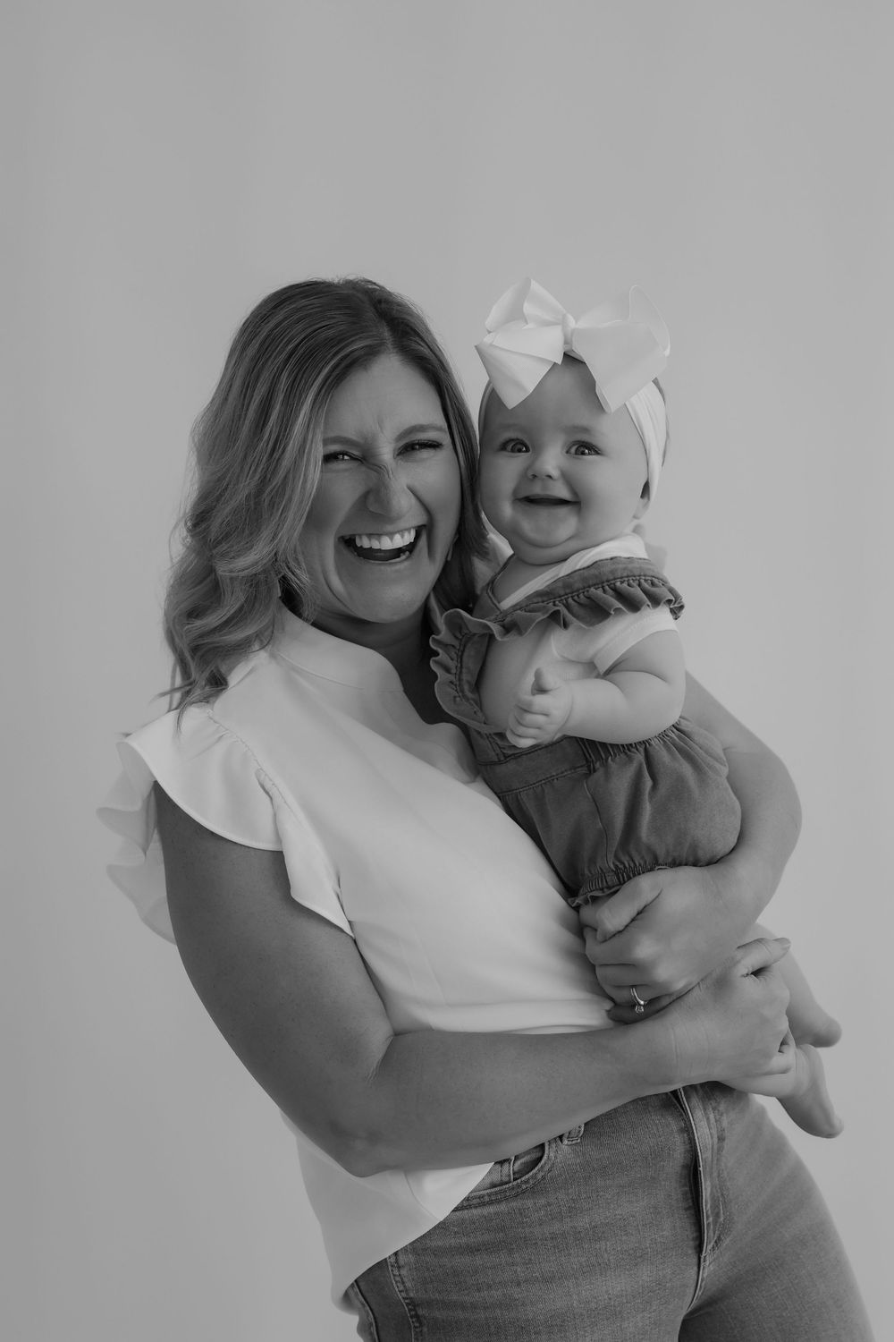 Black and white portrait capturing genuine laughter between adult and baby.