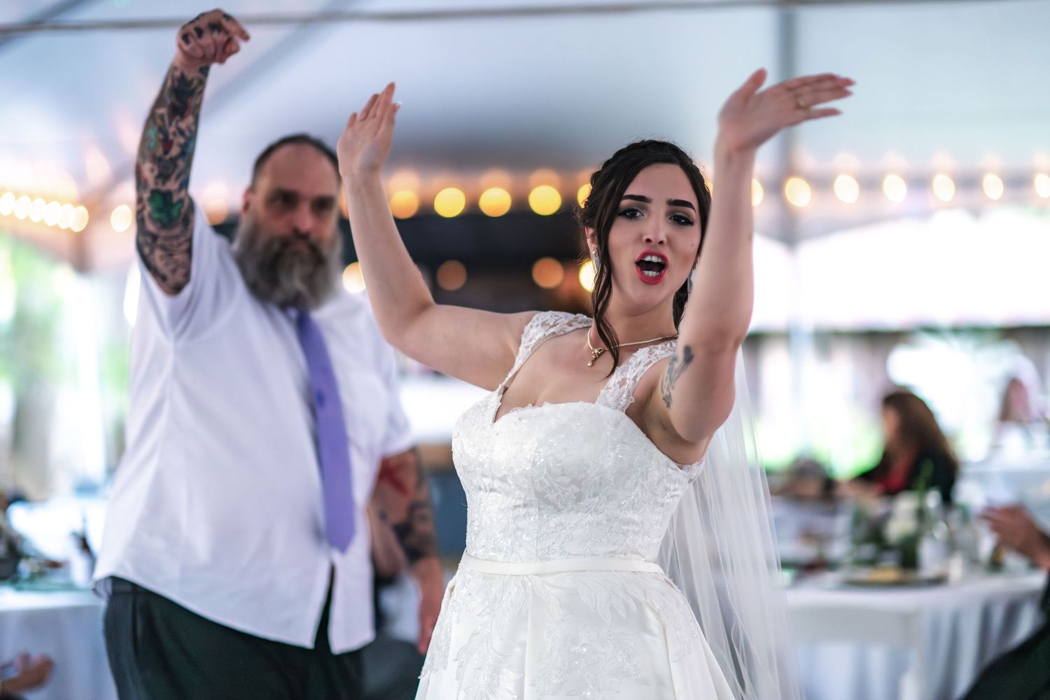 Celebration on the dance floor at a wedding reception as couple energetically dances together with arms raised.