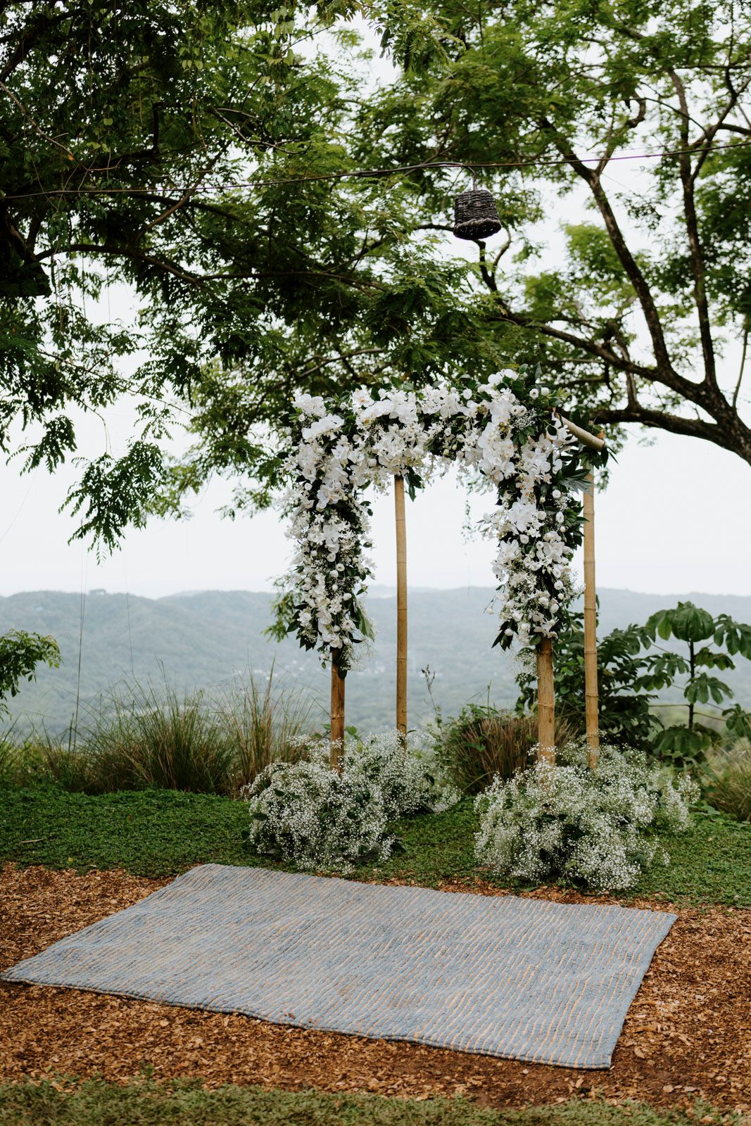 Scenic outdoor wedding ceremony space with mountain views and white floral arrangements.