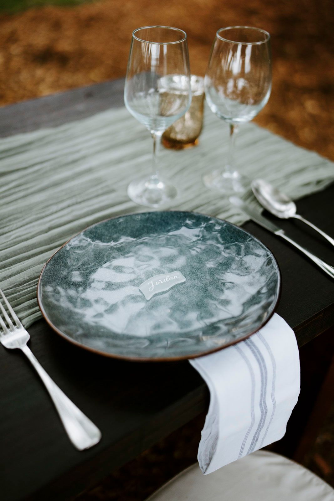 Elegant place setting with marbled gray plate, white napkin, and wine glasses.