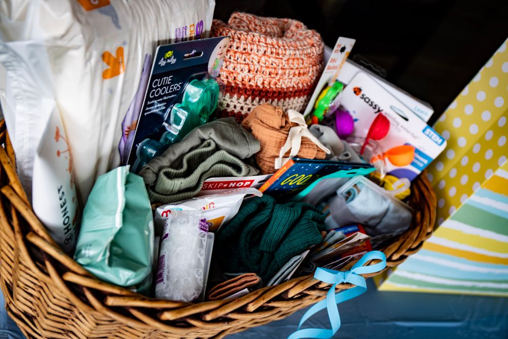 Wicker basket filled with assorted baby clothes and accessories.