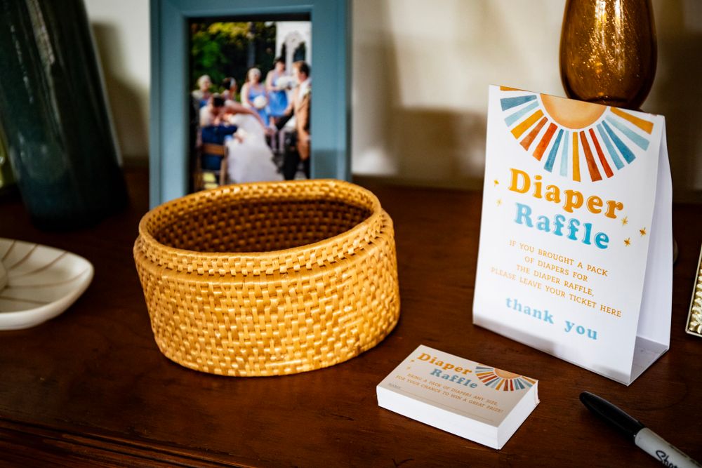 Diaper raffle card displayed next to woven basket on wooden surface.