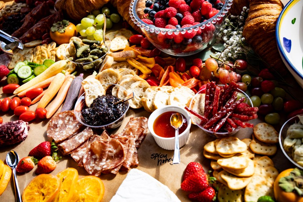 Close up of a colorful grazing table with fresh fruits, meats, cheeses and appetizers artfully arranged.