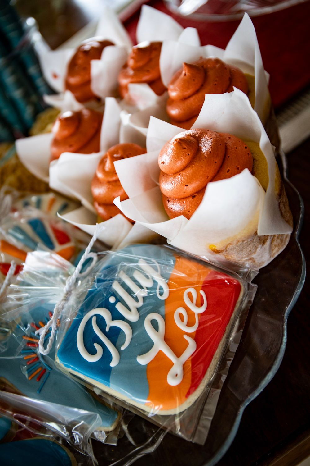Close-up of orange frosted cupcakes and Billy Lee branded cookies on display.