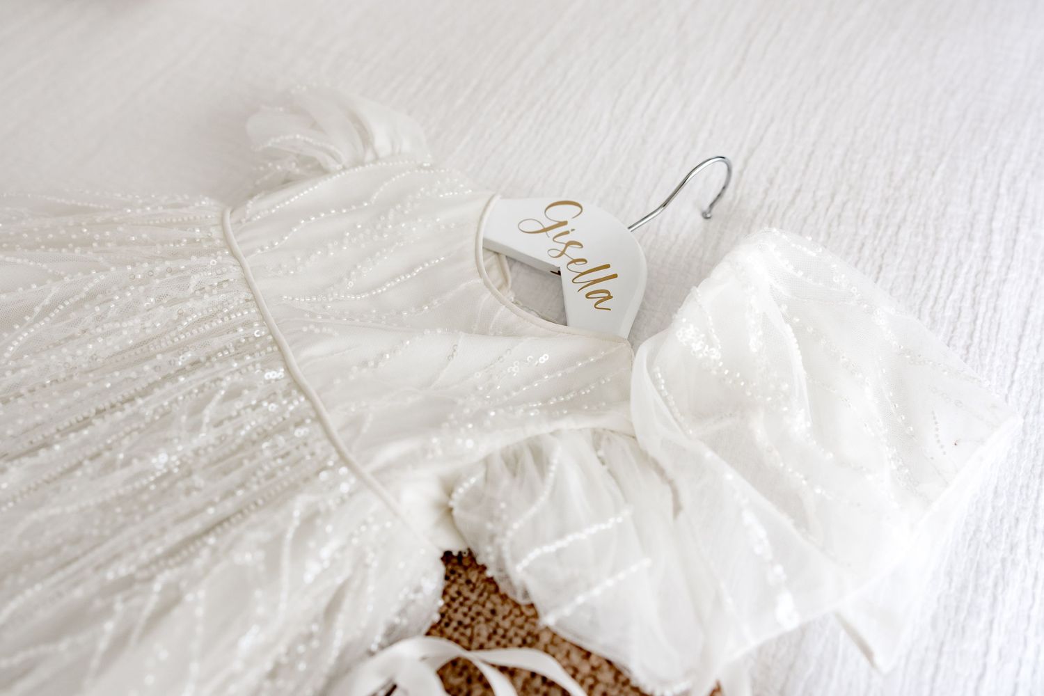 White crumpled cotton fabric with scattered brown organic material photographed on a light textured surface.