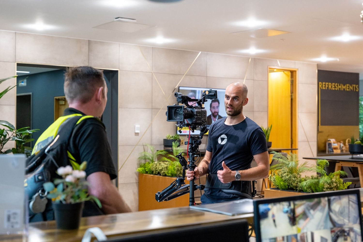 Professional video production team filming content in a modern office setting with camera equipment and lighting.