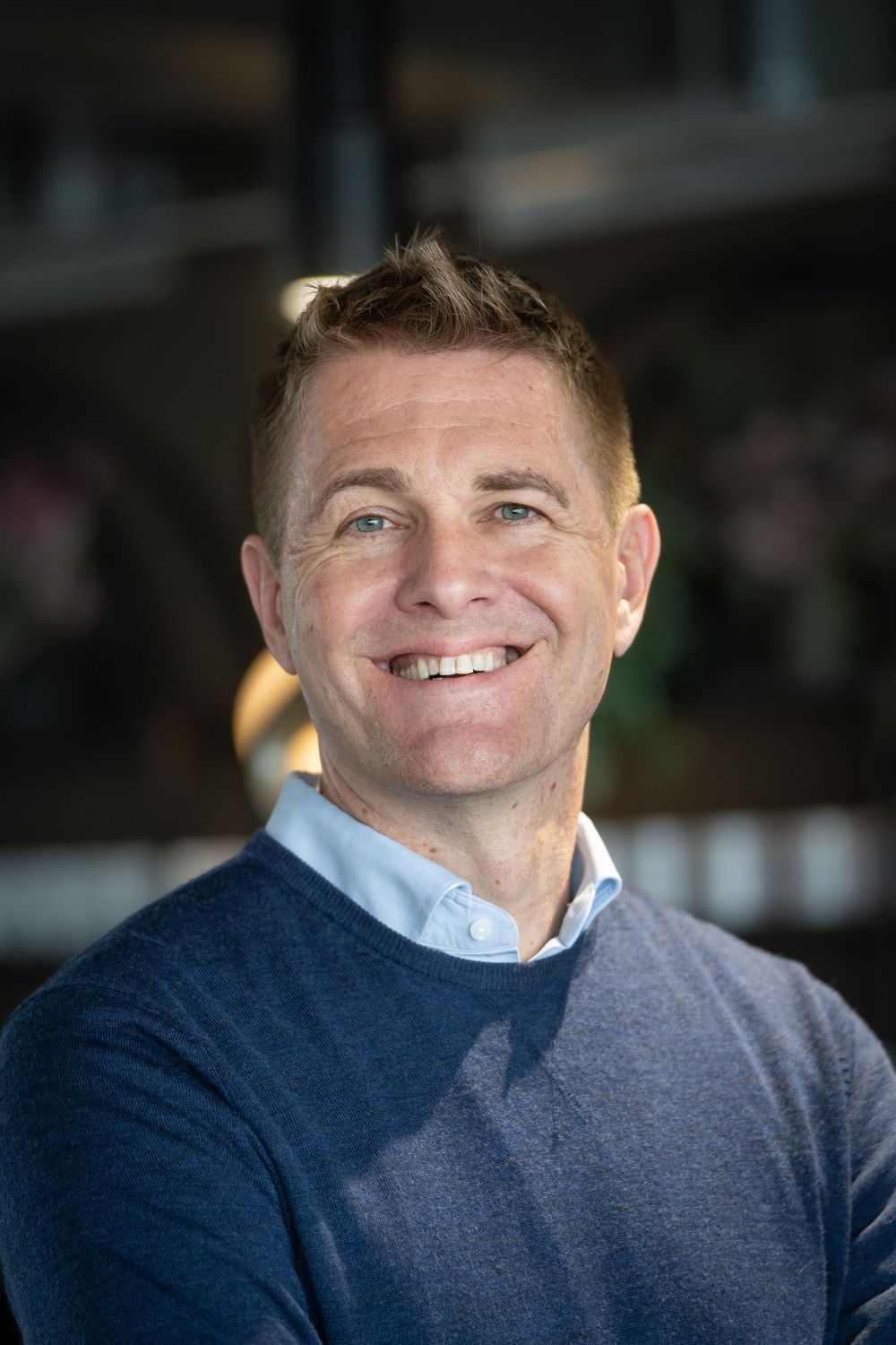 Close-up portrait showing warm smile in navy sweater.