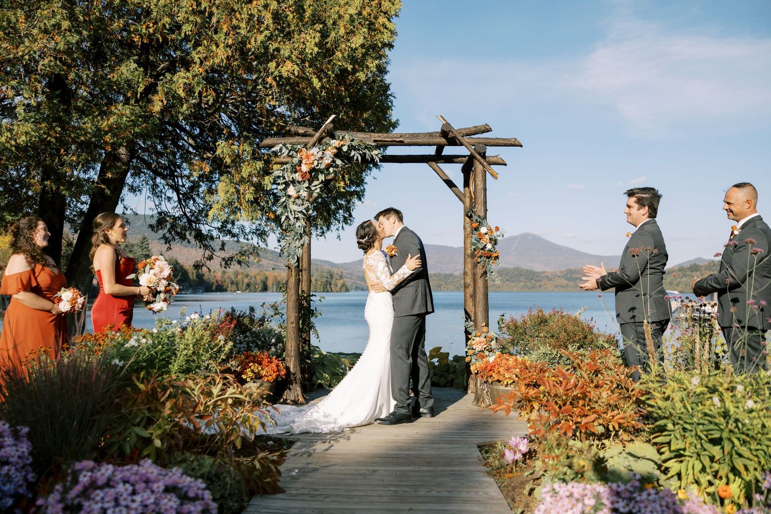 Outdoor wedding ceremony on a scenic mountain overlook with autumn foliage and colorful flowers in the foreground.