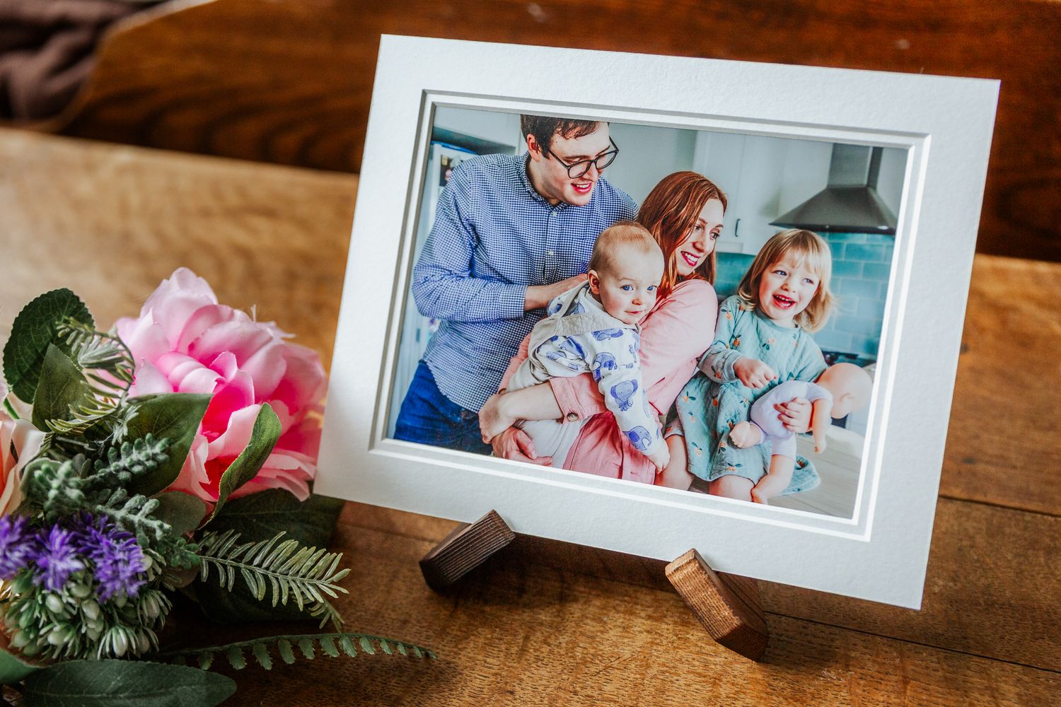 A young family smile and relax as they cuddle in their kitchen. Bristol family photographer