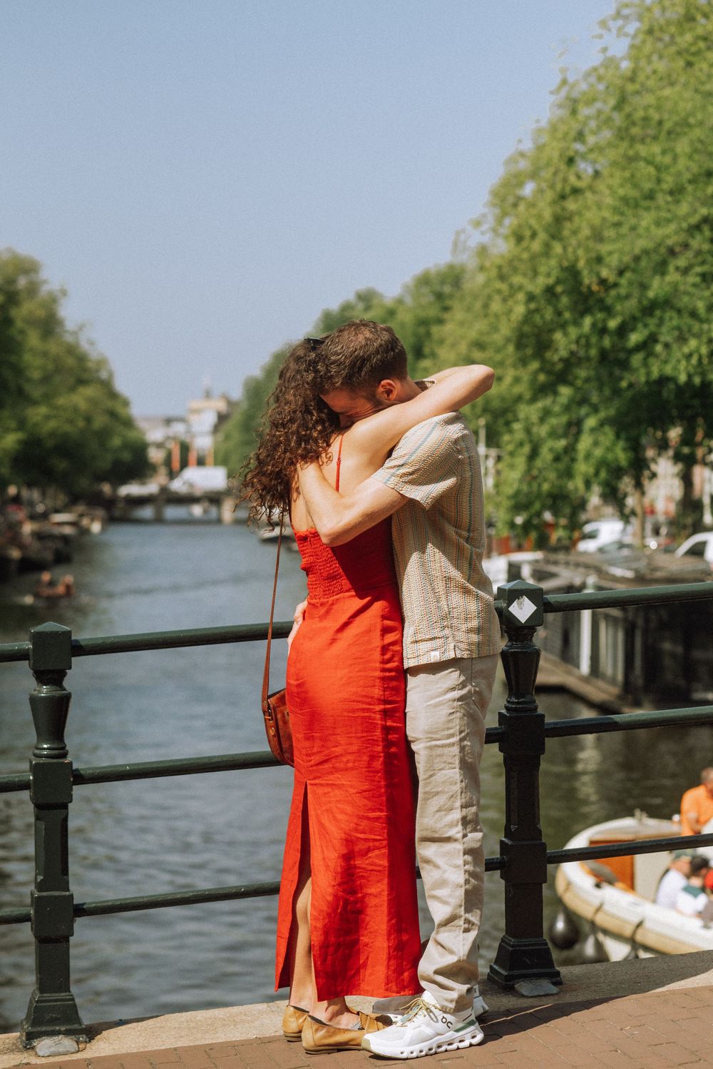 Romantic scene by a canal with two people embracing against a railing.