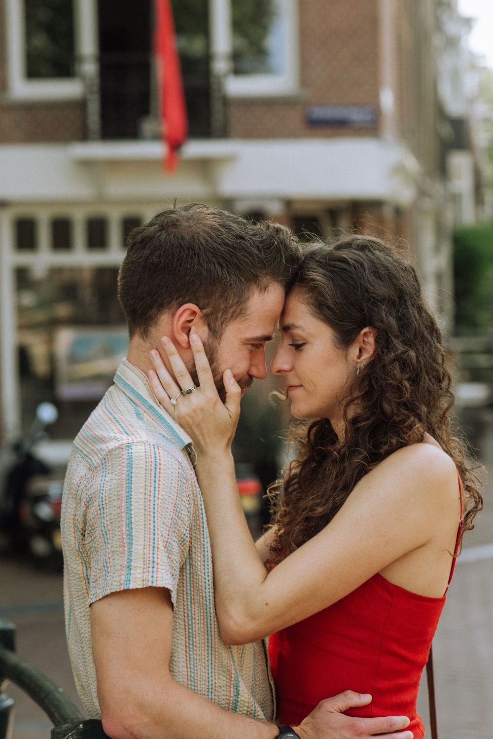 Intimate moment captured between two people in casual attire on a city street.