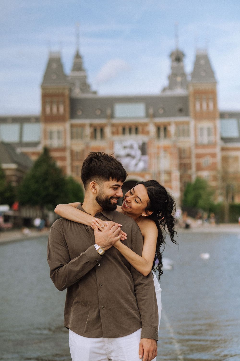 Couple embracing romantically in front of the Rijksmuseum in Amsterdam, Netherlands.