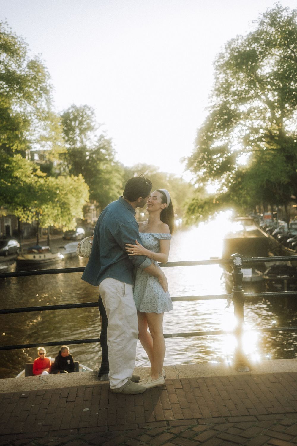 Sunset silhouette of couple by waterfront with golden light shimmering on canal.
