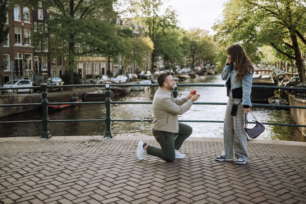 A romantic couple walks along Amsterdam's picturesque canals during autumn.