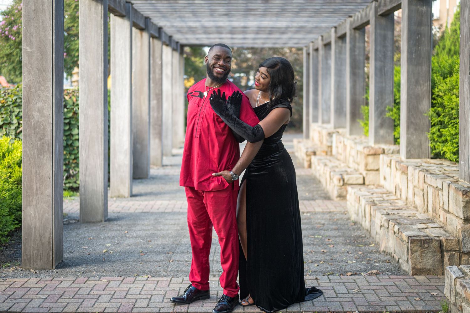 Two people share an intimate moment while dancing together in a covered outdoor walkway with stone columns.
