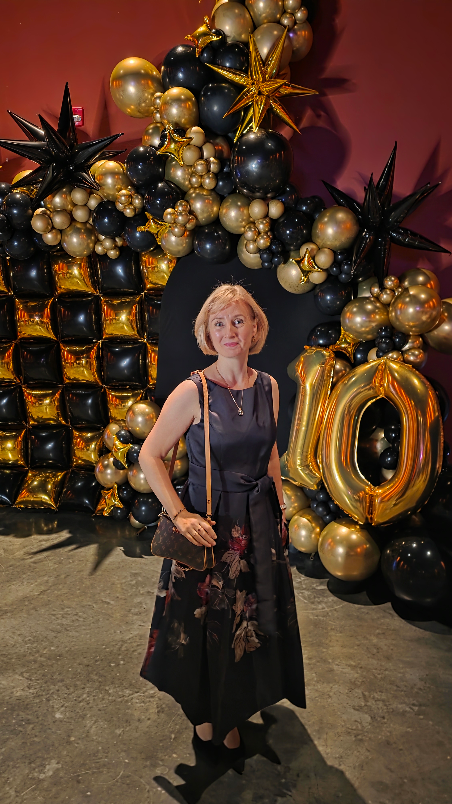 Elegant party setup with black and gold balloon garland and decorative number arrangements against a dark backdrop.