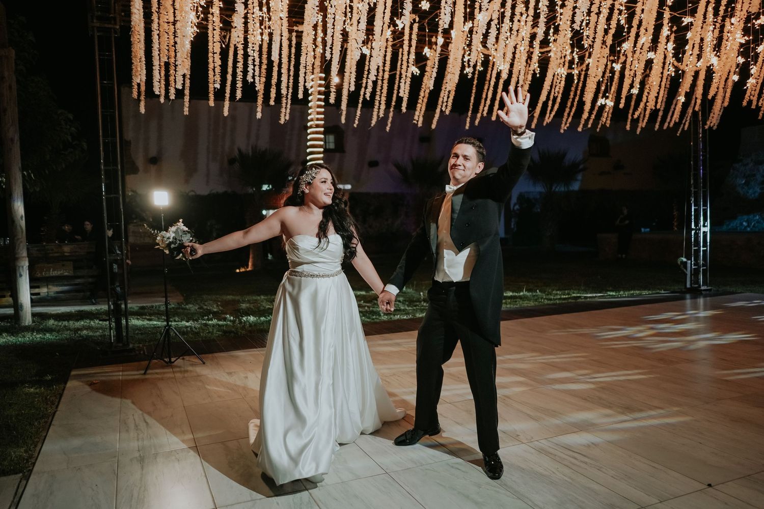 Couple dancing together on an illuminated wooden dance floor during an evening celebration.