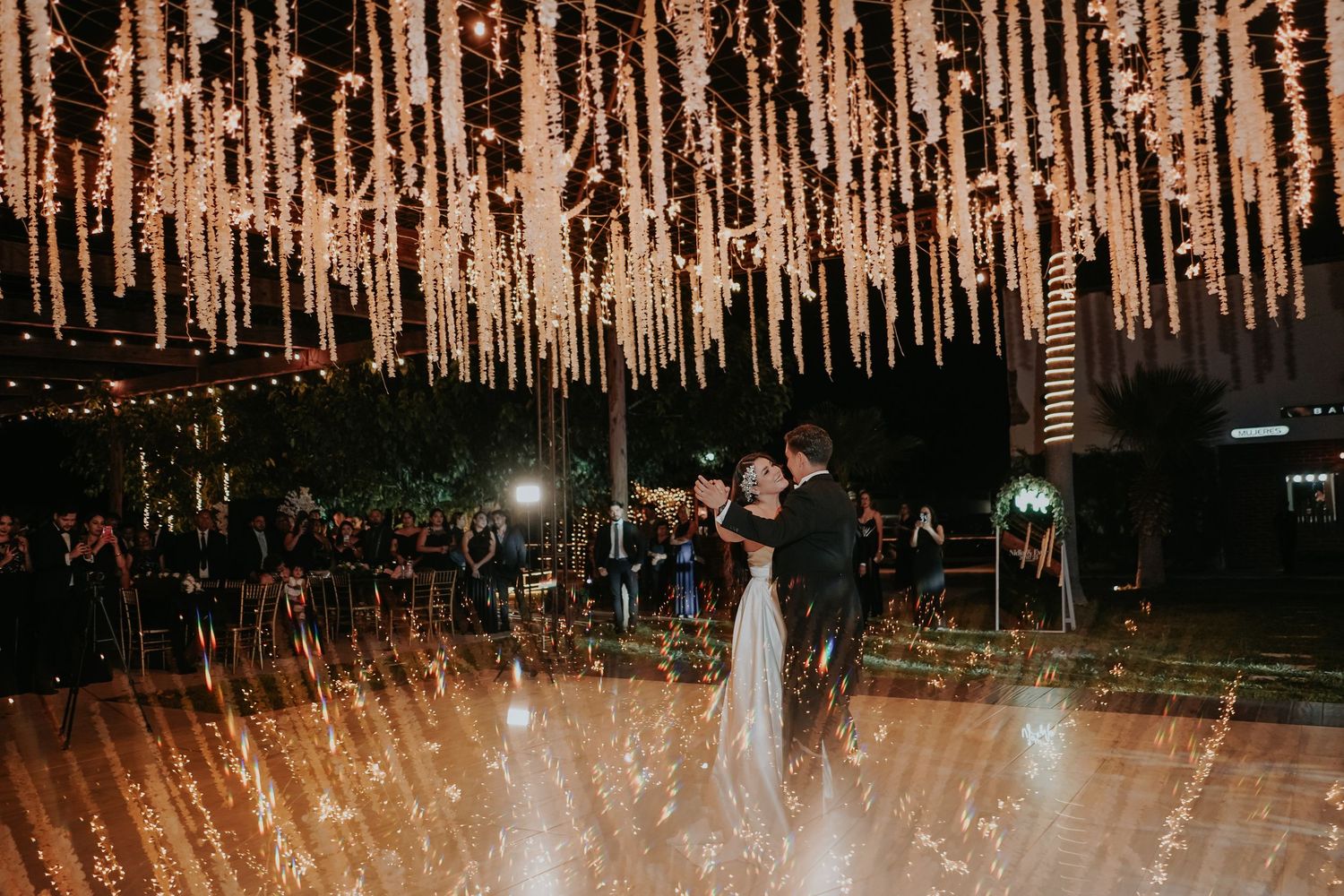 Illuminated crystal strands create a magical ceiling display at an elegant indoor event venue.