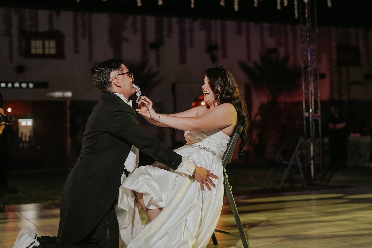 A couple shares a romantic dance together at their wedding reception on a softly lit dance floor.