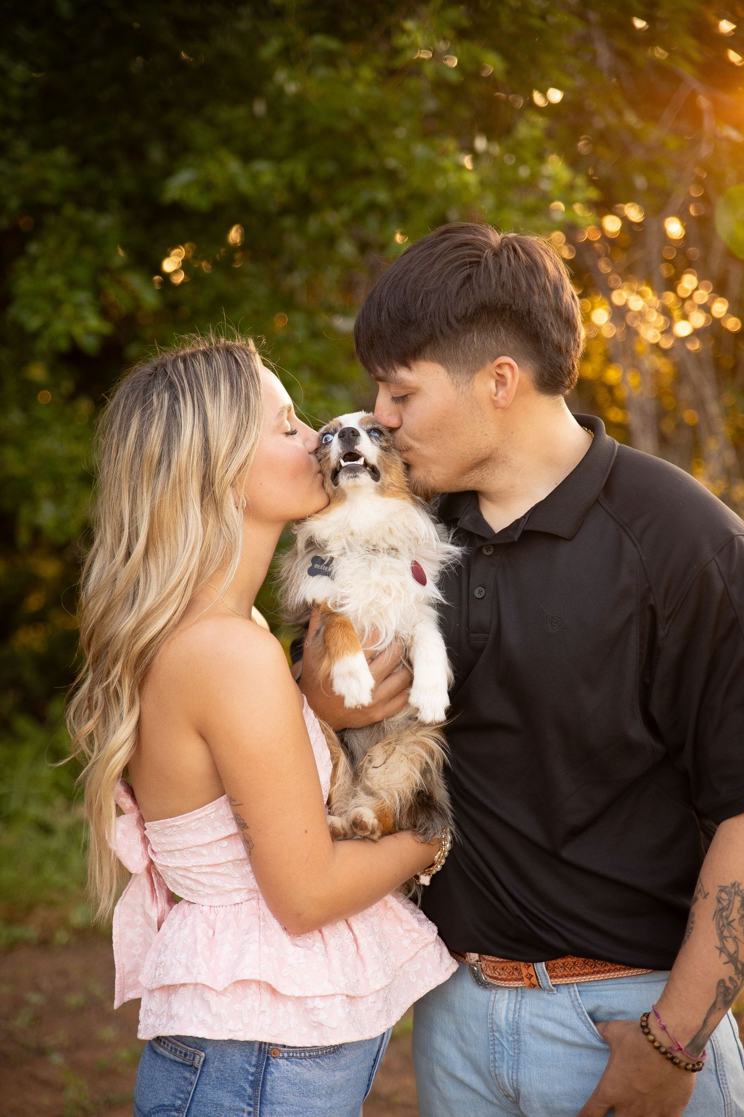 A couple and their small dog share sweet moments together during a sunset photoshoot in a garden setting.