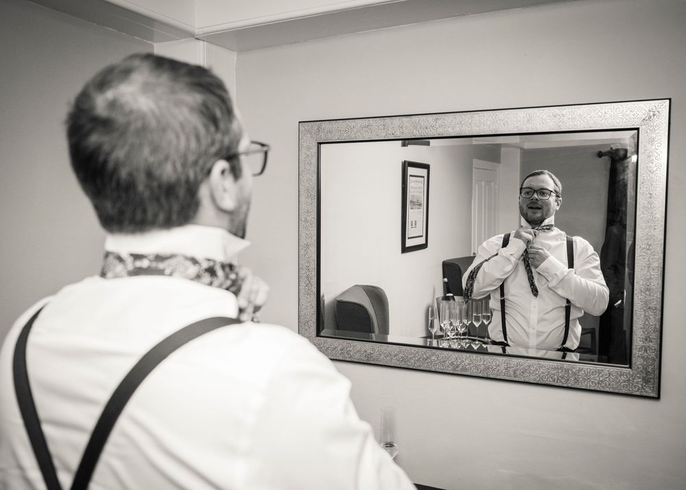 A black and white photo series showing someone in a white shirt looking at themselves in a bathroom mirror.