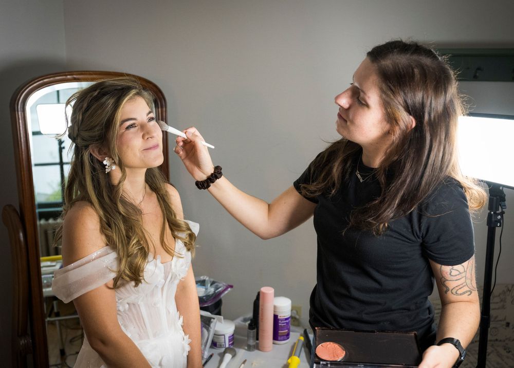 Professional makeup application session with brushes and beauty products in natural lighting.