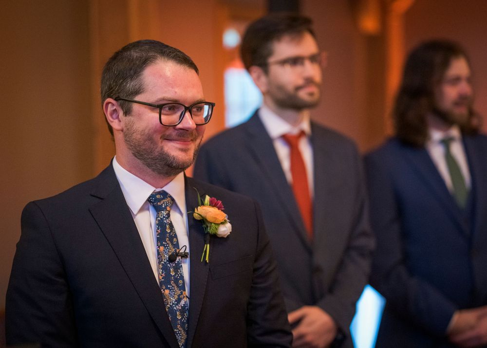 Wedding party members in formal attire gathered in an indoor venue space.