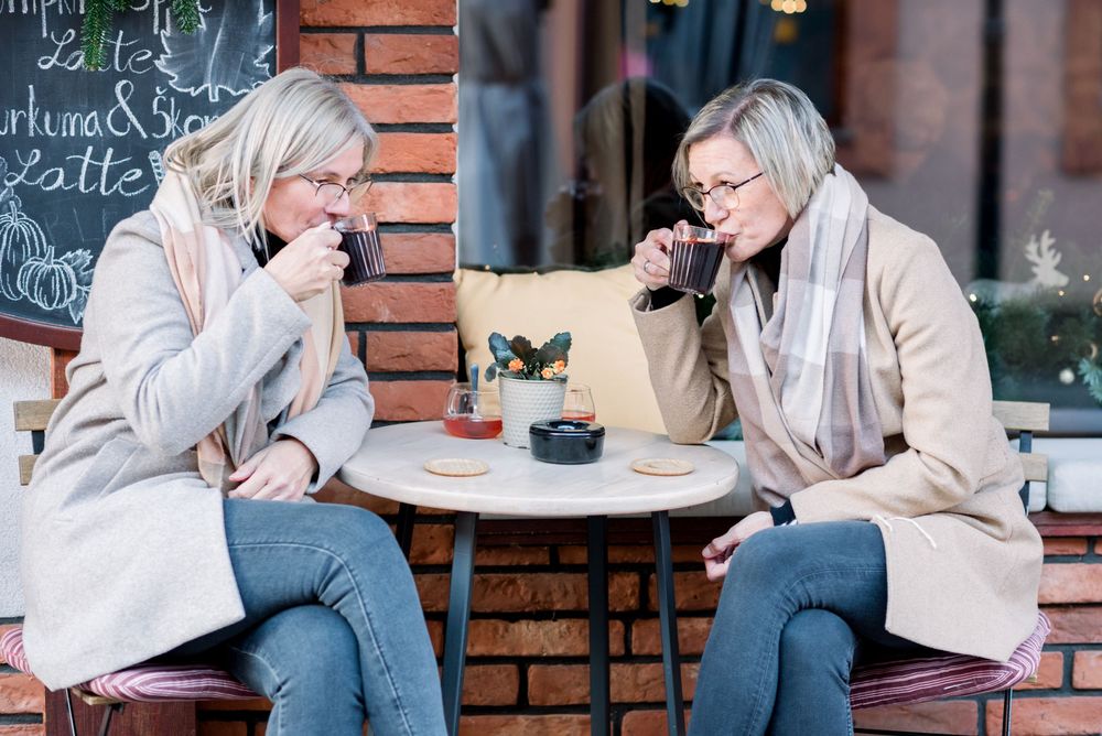 Two people sharing drinks and conversation at outdoor cafe table.