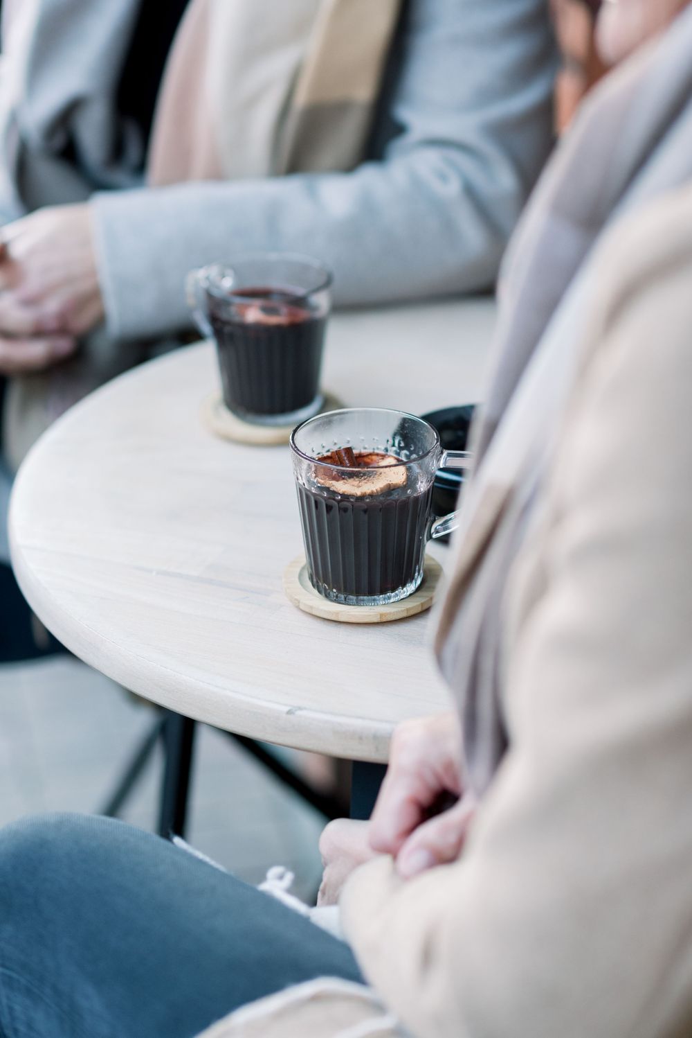 Close-up of coffee drinks in glass cups on white cafe table.