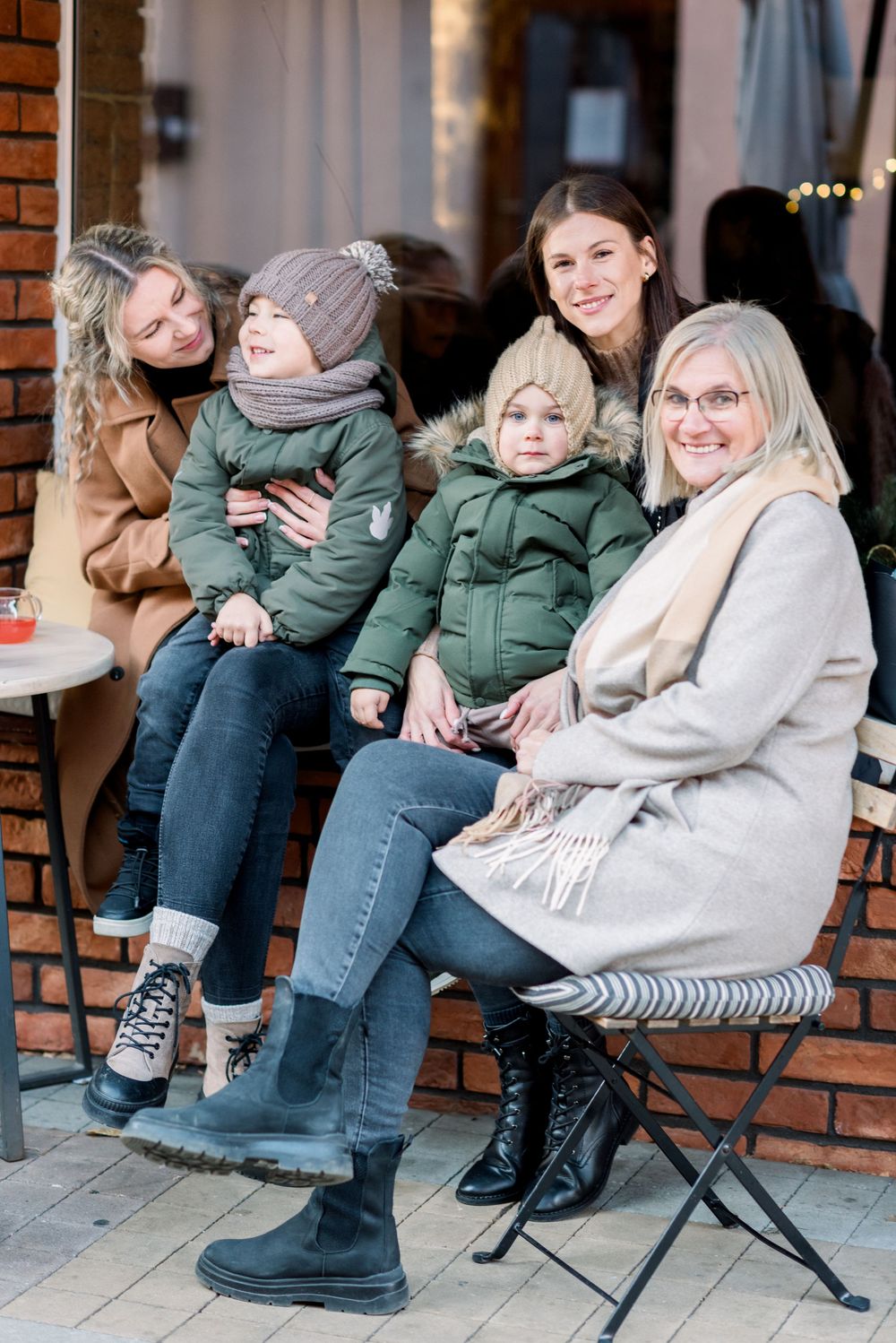 Casual winter gathering at outdoor cafe with brick wall background.