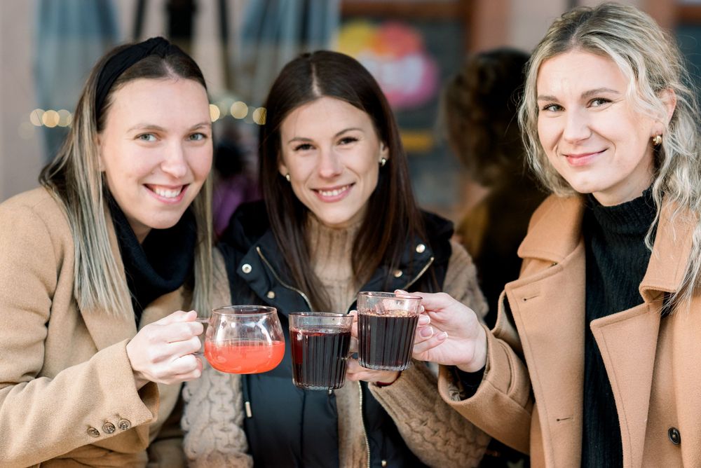 Group enjoying drinks and conversation at a rustic brick-walled cafe patio.