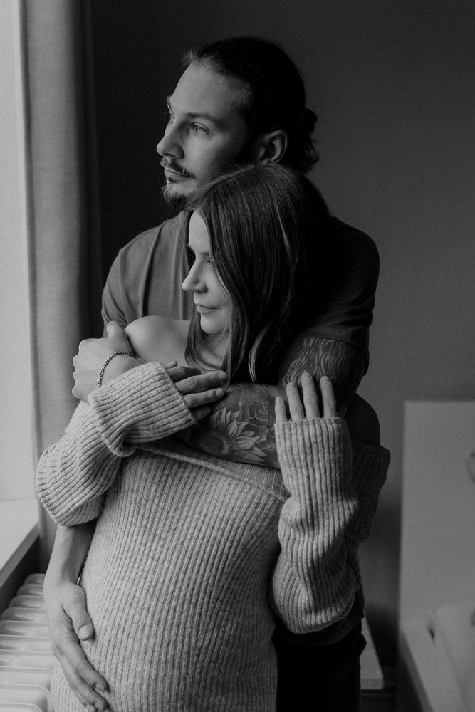 Black and white photo sequence showing a tender embrace between two people in a sweater near a window.