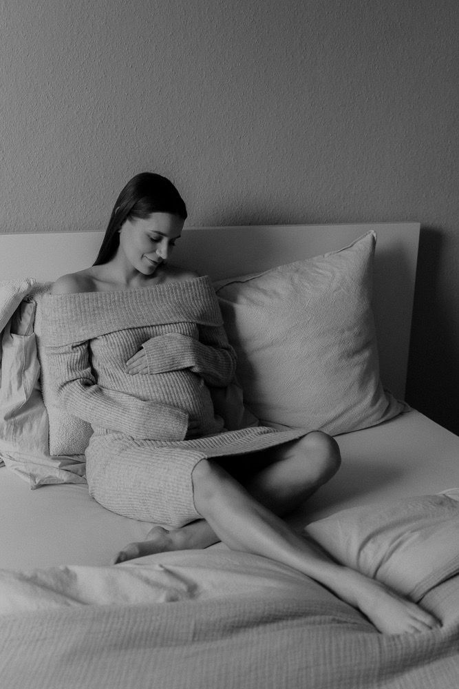 Black and white artistic photo of a person lounging comfortably on bed linens.