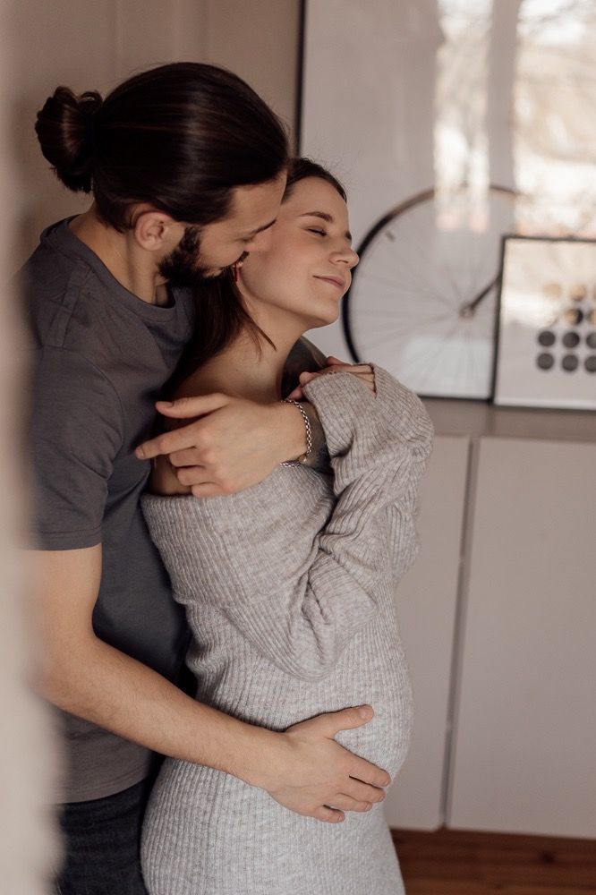 A romantic couple embraces tenderly in a home setting wearing grey and black clothing.