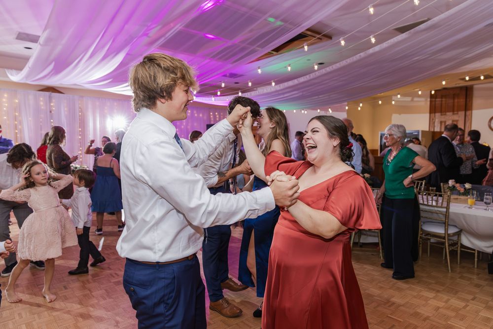 Wedding guests dancing and celebrating on a dance floor illuminated with purple lighting at the Old Courthouse in London, Ontario.