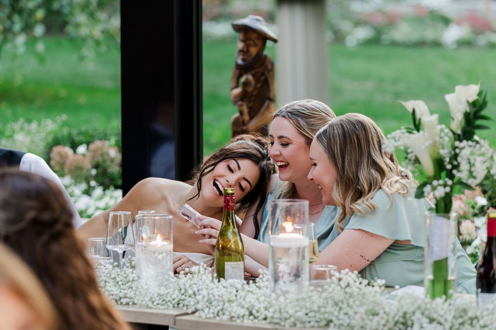 Bride sharing an intimate moment laughing with her bridesmaids during the reception at The Wren House in St. Jacobs, Ontario.