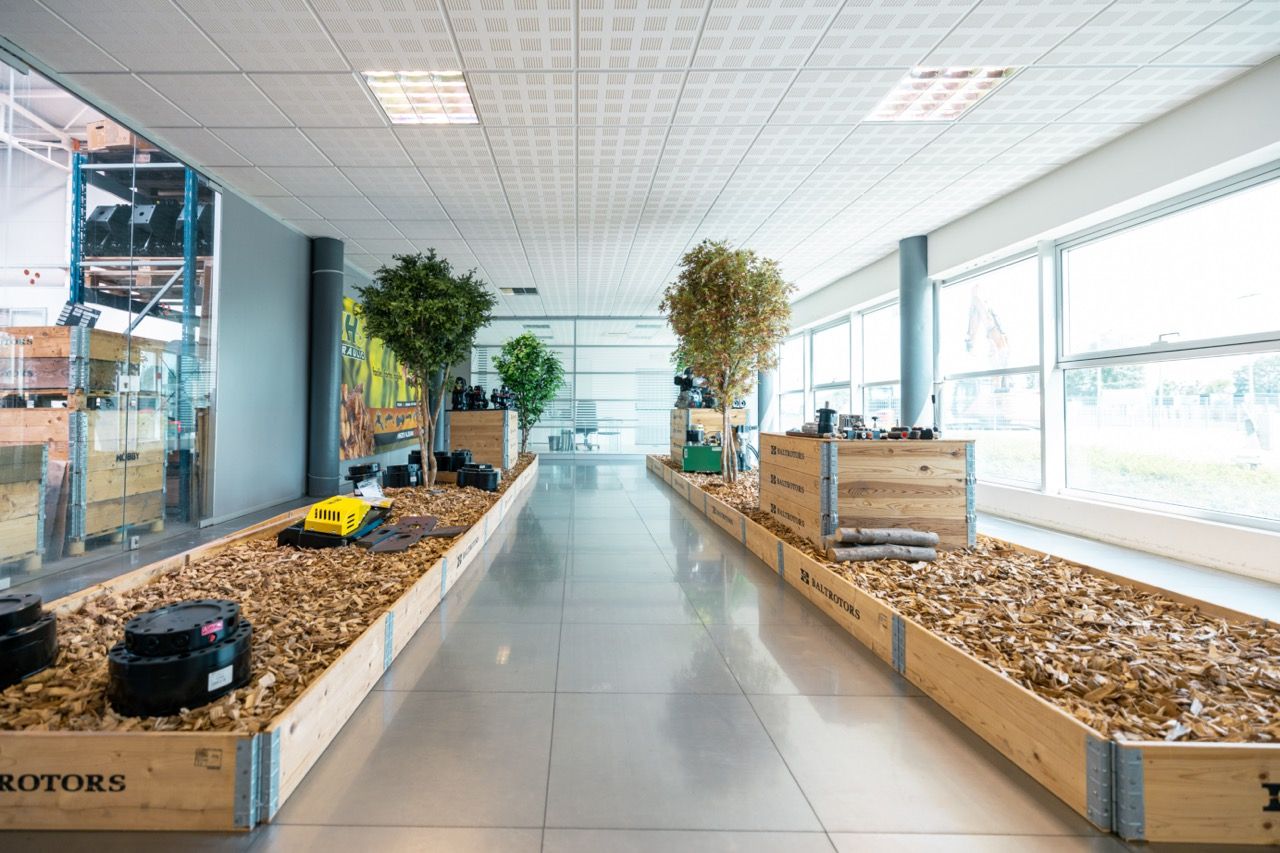Modern office hallway with white walls, suspended ceiling, and natural lighting from large windows.