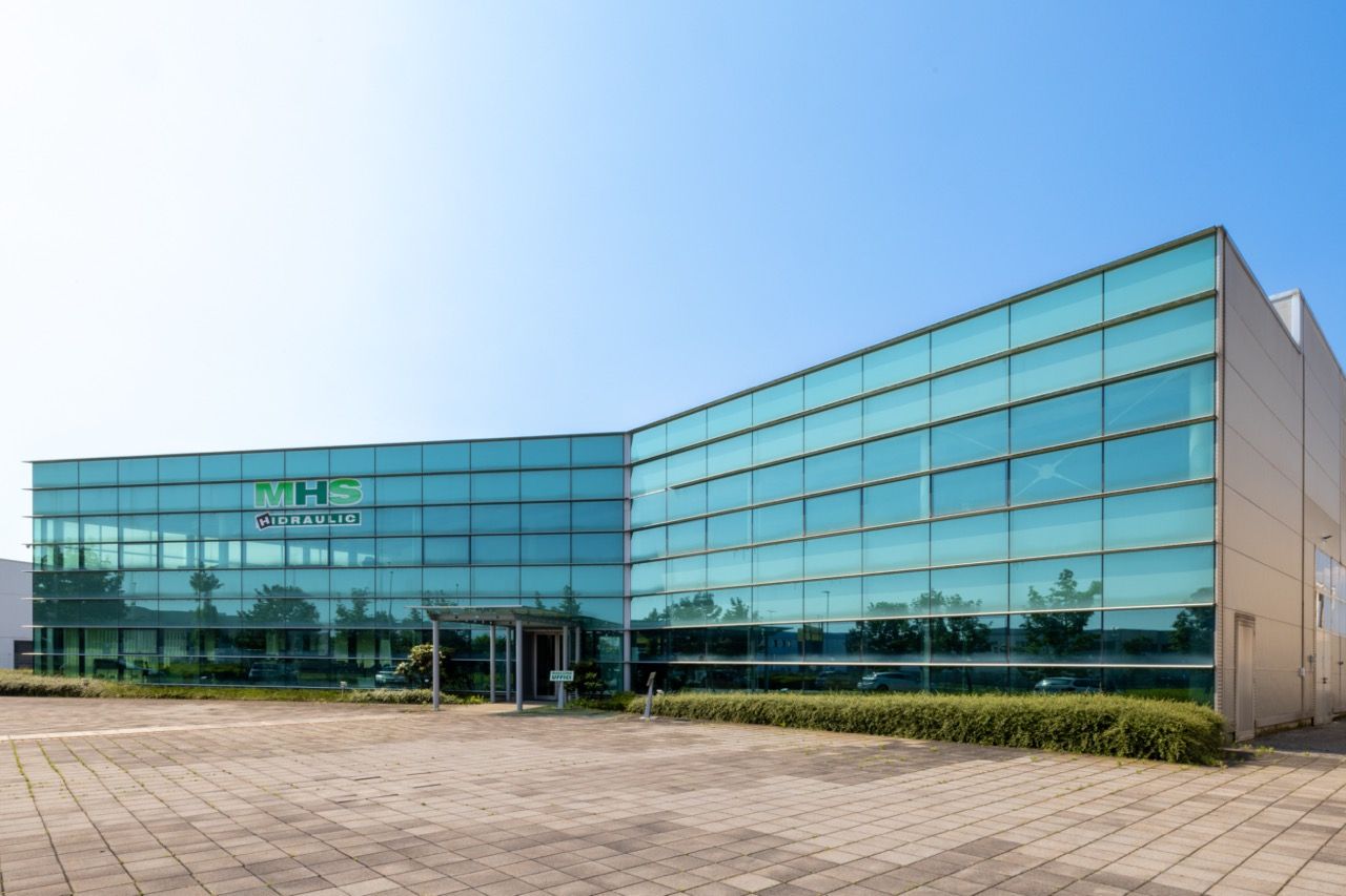 Modern glass office building exterior with curved facade photographed from different angles against blue sky.