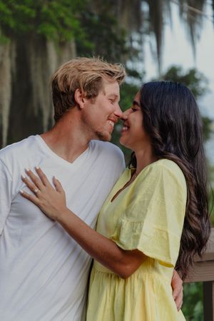 Intimate couple shares tender moments while wearing yellow and white against a natural backdrop.