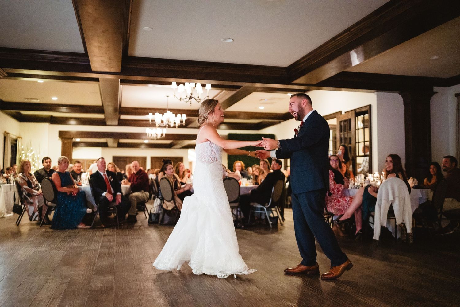 Wedding reception guests dance together on a dimly lit dance floor during an evening celebration.