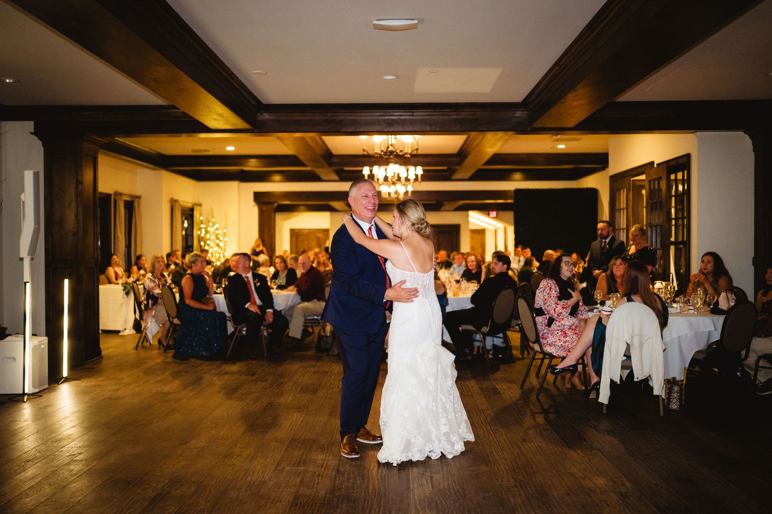 Wedding guests dance and celebrate on a dimly lit dance floor at an elegant reception venue.