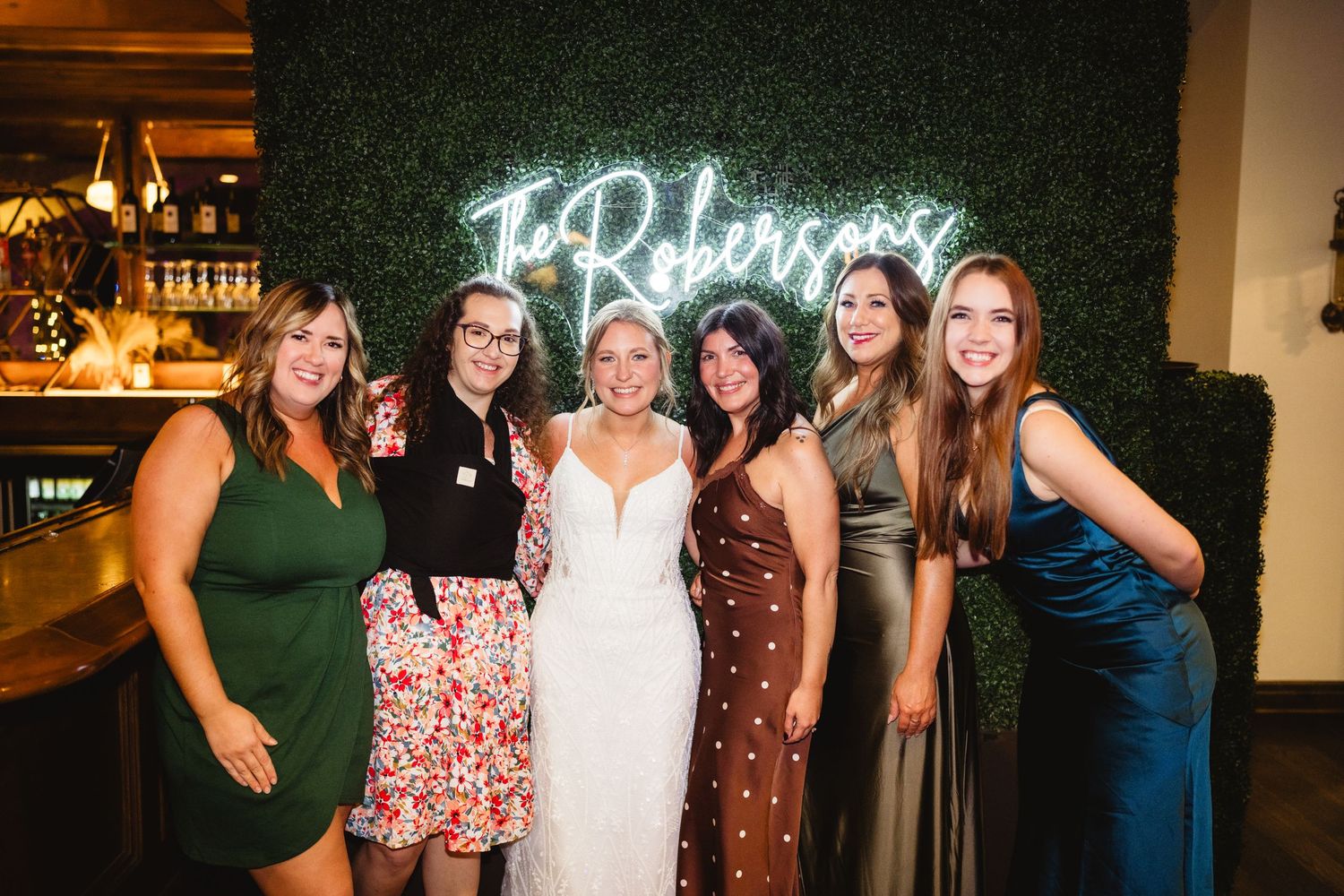 Wedding party guests pose and smile together during an evening reception celebration.