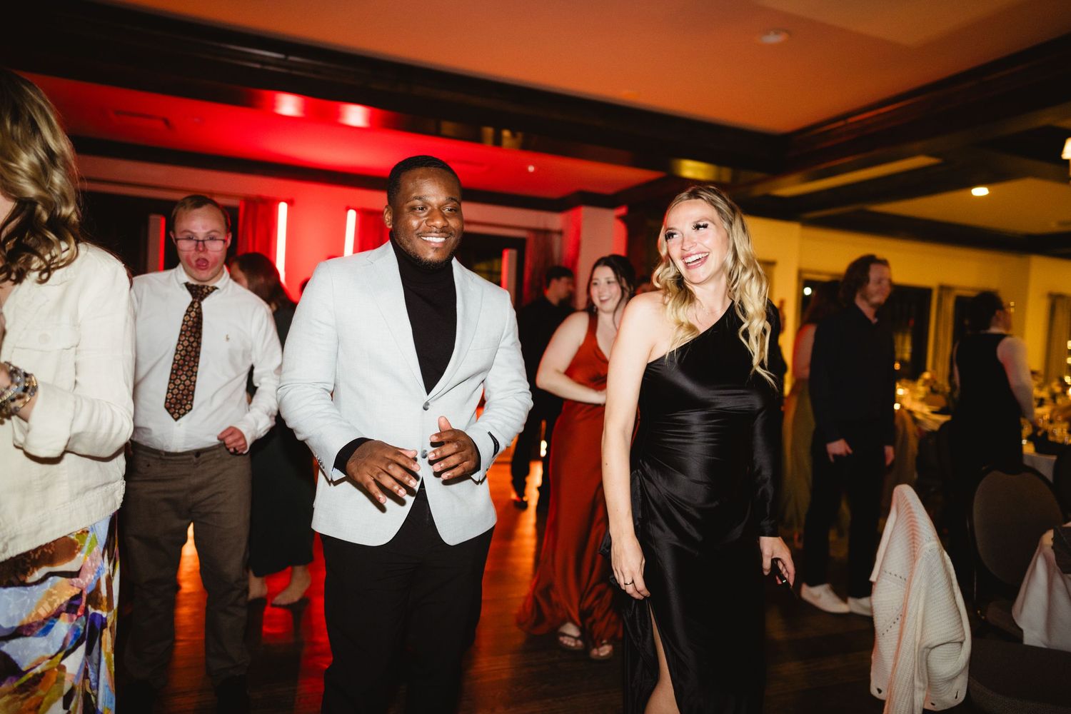 Wedding reception dance floor illuminated in red lighting as guests dance and celebrate.