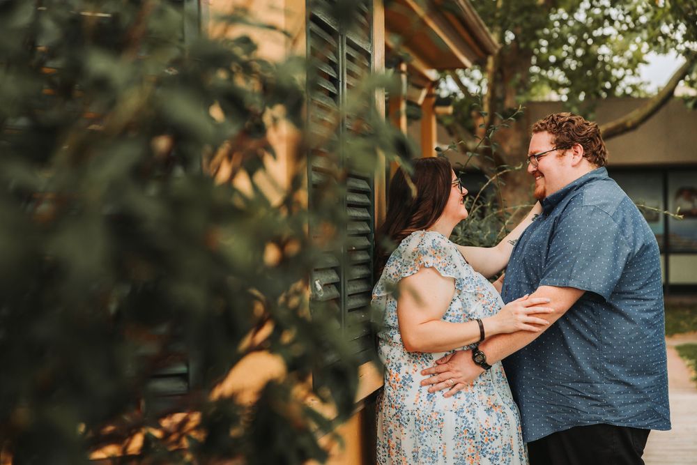 A couple dances together in a garden setting during golden hour as sunlight filters through tree branches.