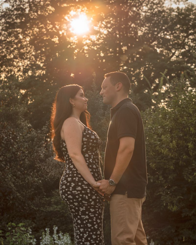 A couple shares a romantic moment at sunset in a garden setting with golden sunlight filtering through trees.