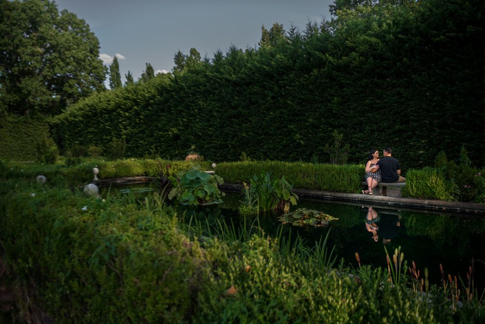 A romantic photoshoot in a serene garden landscape with trees and natural scenery.