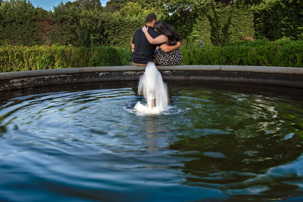 Rippling water in a dark pond with fountain spray creating concentric circles.