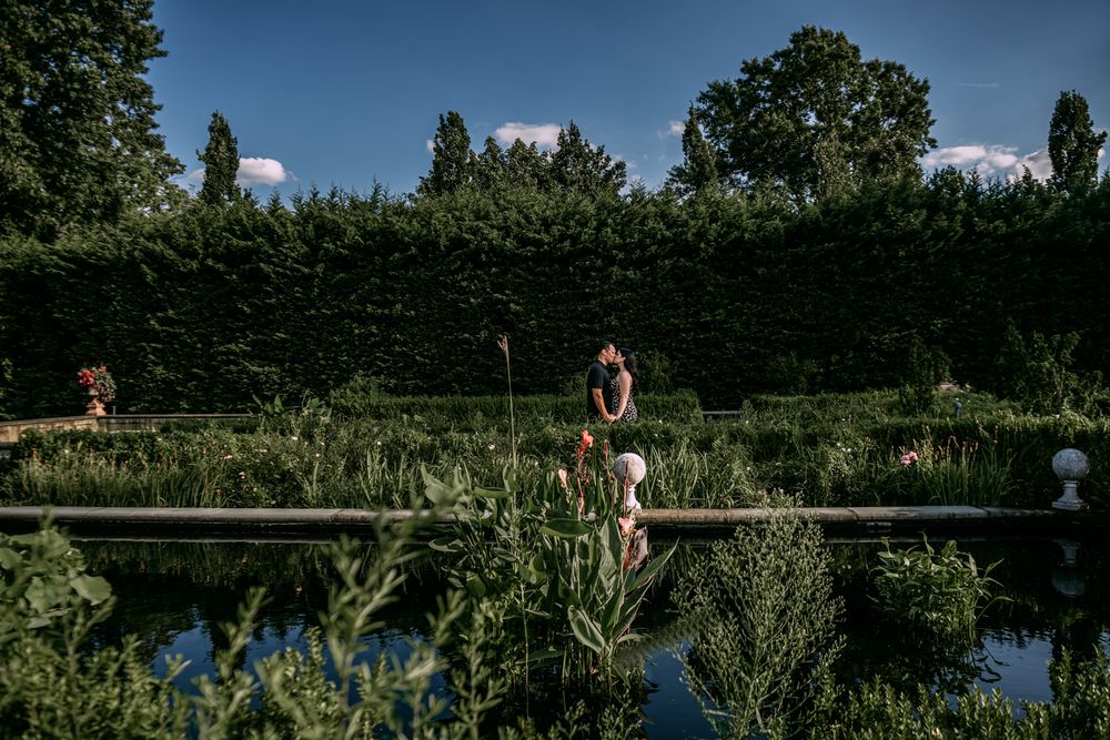 A scenic garden path with reflecting pool surrounded by lush greenery and hedges.